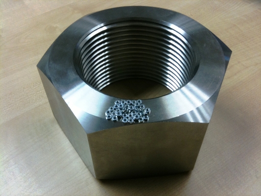 Machined M110 hex nut with standard small nuts sitting inside the thread for scale